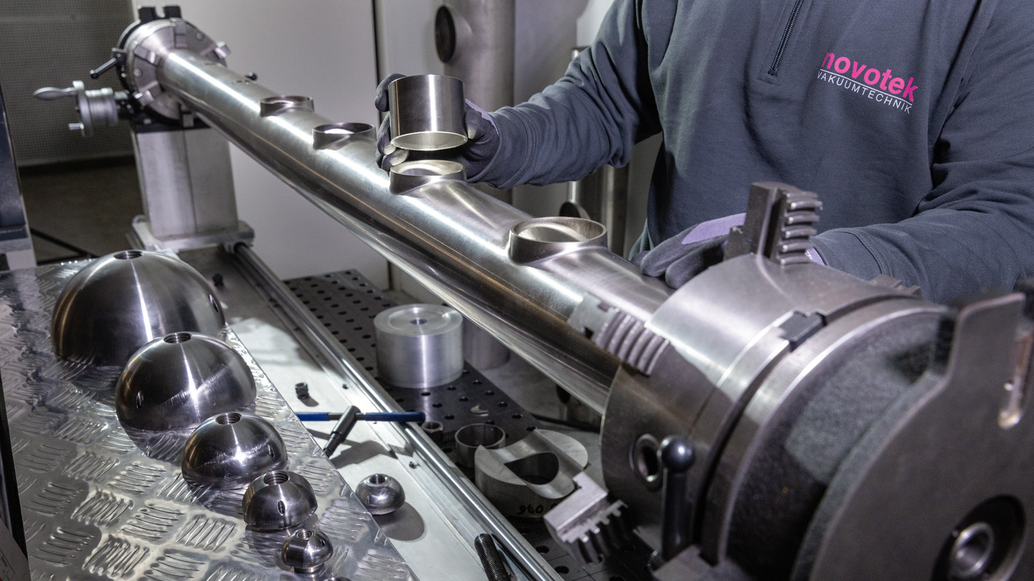 Mitarbeiter in Werkstatt steht an Maschine zum Aushalsen